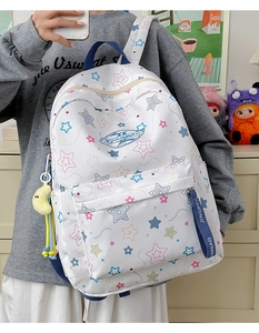 Detail of white star-patterned backpack showing navy strap and yellow moon charm