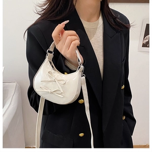 Detail of a creamy white patent leather mini bag with sweet decorative double bows