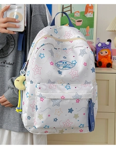 Detail of white backpack with colorful star patterns and a yellow moon plush pendant