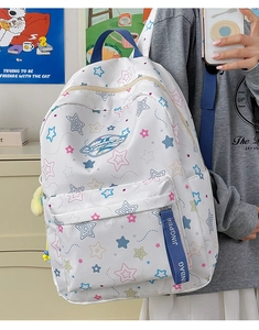 Detail of white star-patterned backpack with colorful stars and plush ball keychain