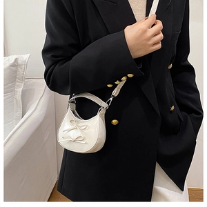 Detail of white bow shoulder bag with glossy patent leather and gold hardware
