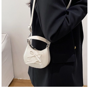 Detail of white patent leather handbag featuring sweet bow accents and a top handle