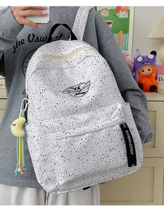 Close-up of white waterproof backpack with black polka dots and plush moon charm