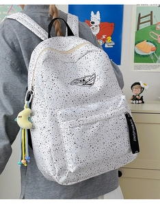 Detail view of white splatter pattern backpack with cute moon plush and decorative ribbons