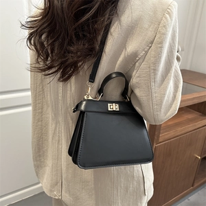 Classic black trapeze handbag with gold twist lock and crossbody strap for women