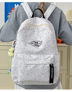 Detail of waterproof backpack with ink splatter dots and yellow moon plush charm accessory