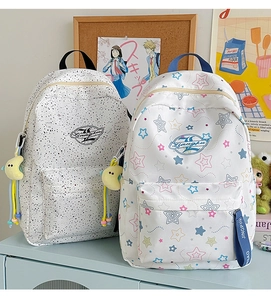 Close-up of minimalist polka dot and star pattern backpacks with plush moon charms