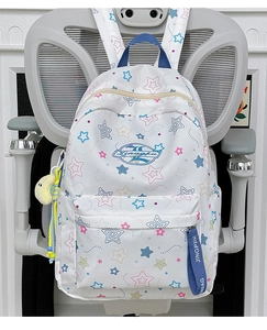 Detail of white star-patterned backpack with yellow moon plush pendant on office chair