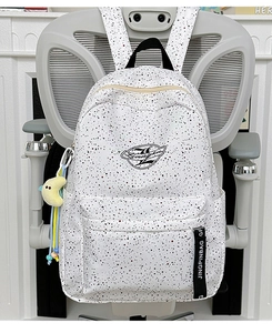 Detail of white splatter pattern backpack with yellow moon plush toy and strap decor