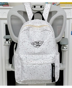 Detail of white splash-pattern backpack showing the zipper pocket and branded strap