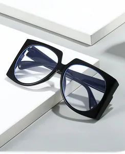 Macro detail of oversized black frame glasses with blue light blocking lenses on a white block