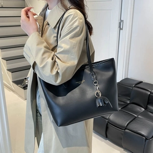 Minimalist black leather tote bag with compartments shown on a model in a casual setting