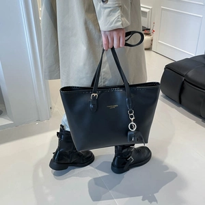 Minimalist black faux leather tote bag with gold lettering and charm for women's daily use