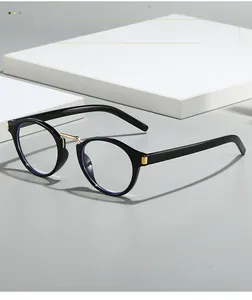Detail of oval black frame glasses with gold metal bridge and minimalist hinges