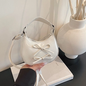 White crescent handbag with sweet bow knots and adjustable strap in a minimalist setting