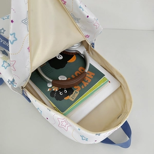 White star pattern backpack showing large interior capacity with books and headphones
