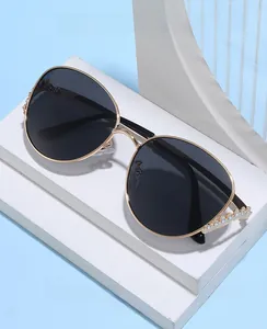 Détail de charnière en métal doré avec couronne de strass sur lunettes noires