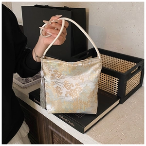 Detalle de bolso chino con motivos de paisajes dorados y decoraciones de borlas plateadas