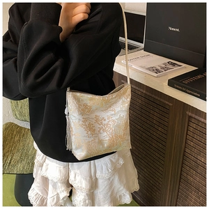 Detail showing traditional Chinese landscape embroidery and white tassel on the crossbody bag