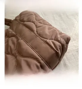 Close-up of brown quilted nylon tote bag featuring wavy stitching and white contrast seams