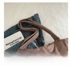 Detail of quilted tote bag featuring a padded handle and smooth satin finish in soft brown