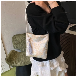 Detail of white jacquard bucket bag featuring gold Chinese landscape embroidery and lilac tassel