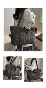 Close-up of wavy quilted tote bag in dark brown with glossy finish and long handles