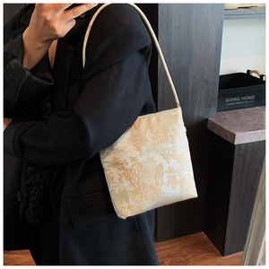 Detail of embroidered shoulder bag featuring traditional landscape pattern on silk fabric