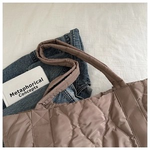 Top-down view of a taupe quilted puffer tote bag with wave stitching on white fabric