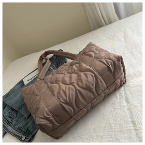Detail of coffee brown quilted tote bag showing soft puffy waves and premium texture