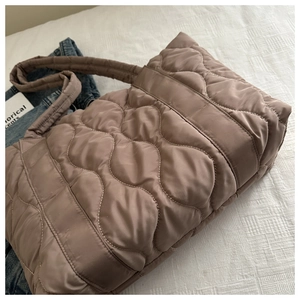 Detail of cocoa quilted tote bag with wave stitching on silky nylon fabric texture