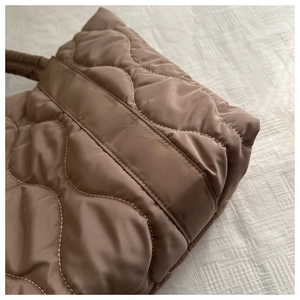 Close-up of brown quilted down tote bag showing wavy stitching and soft nylon texture