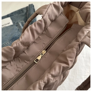 Detail view of the golden metal zipper closure and quilted texture on the brown tote bag