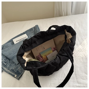 Spacious interior of black quilted tote bag showing large capacity for books and essentials
