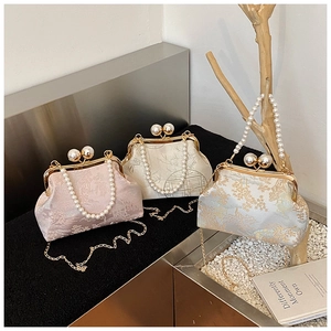 Close-up of jacquard evening clutch bags with pearl handles and ornate floral patterns