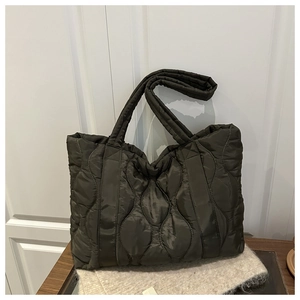Detail showing the wavy quilted texture of this olive green oversized puffer tote bag