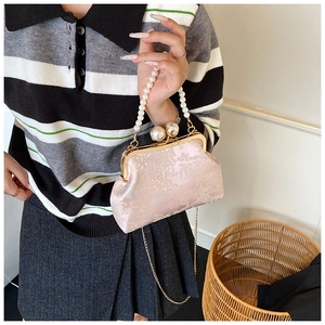 Detailed texture of pink jacquard fabric on a silk clutch with pearl chain handle