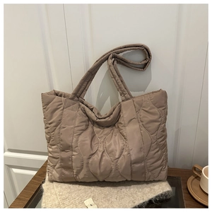 Detailed wave quilted texture on large brown puffer tote bag with wide soft handle