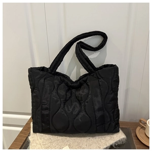 Detail of black quilted tote bag with wavy stitching on premium padded nylon fabric