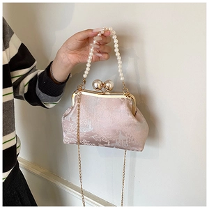 Detailed texture of pink jacquard embroidery bag with pearl handle and metal clasp