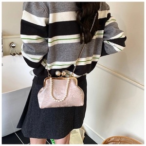 Détail d'un sac en jacquard rose avec poignée en perles et chaîne dorée sur mannequin