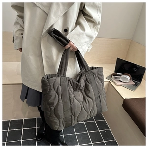 Close-up of quilted wave pattern on large olive tote bag worn by a model in city setting