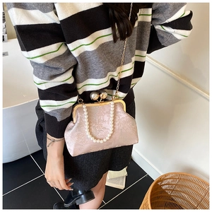 Close-up of pink jacquard shell bag with pearl handle and golden kiss-lock chain