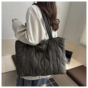 Detail of olive green quilted tote bag featuring soft wave stitching and wide shoulder strap