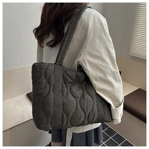 Quilted nylon tote bag with wave stitching and spacious design shown on a model's shoulder