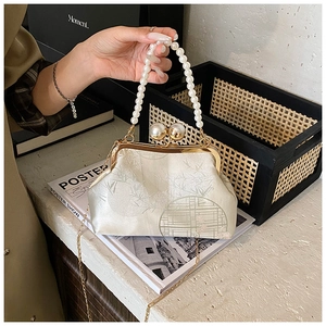 Detailed close-up of champagne jacquard handbag with pearl handle and metal clasp