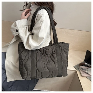 Detail of quilted tote bag featuring wave stitching and wide padded shoulder strap