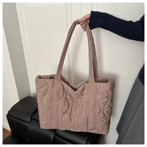 Close-up of wavy quilted tote bag in dusty pink with soft padded texture and handles