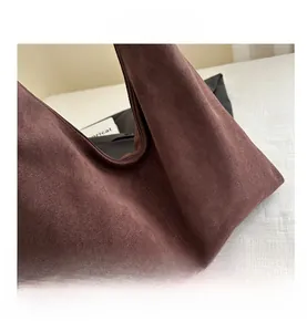 Detail shot of smooth zipper closure and neat stitching on dark brown suede tote bag