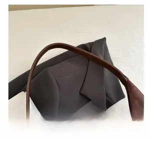 Detail view of the brown leather handle stitching and suede splicing on a large tote bag